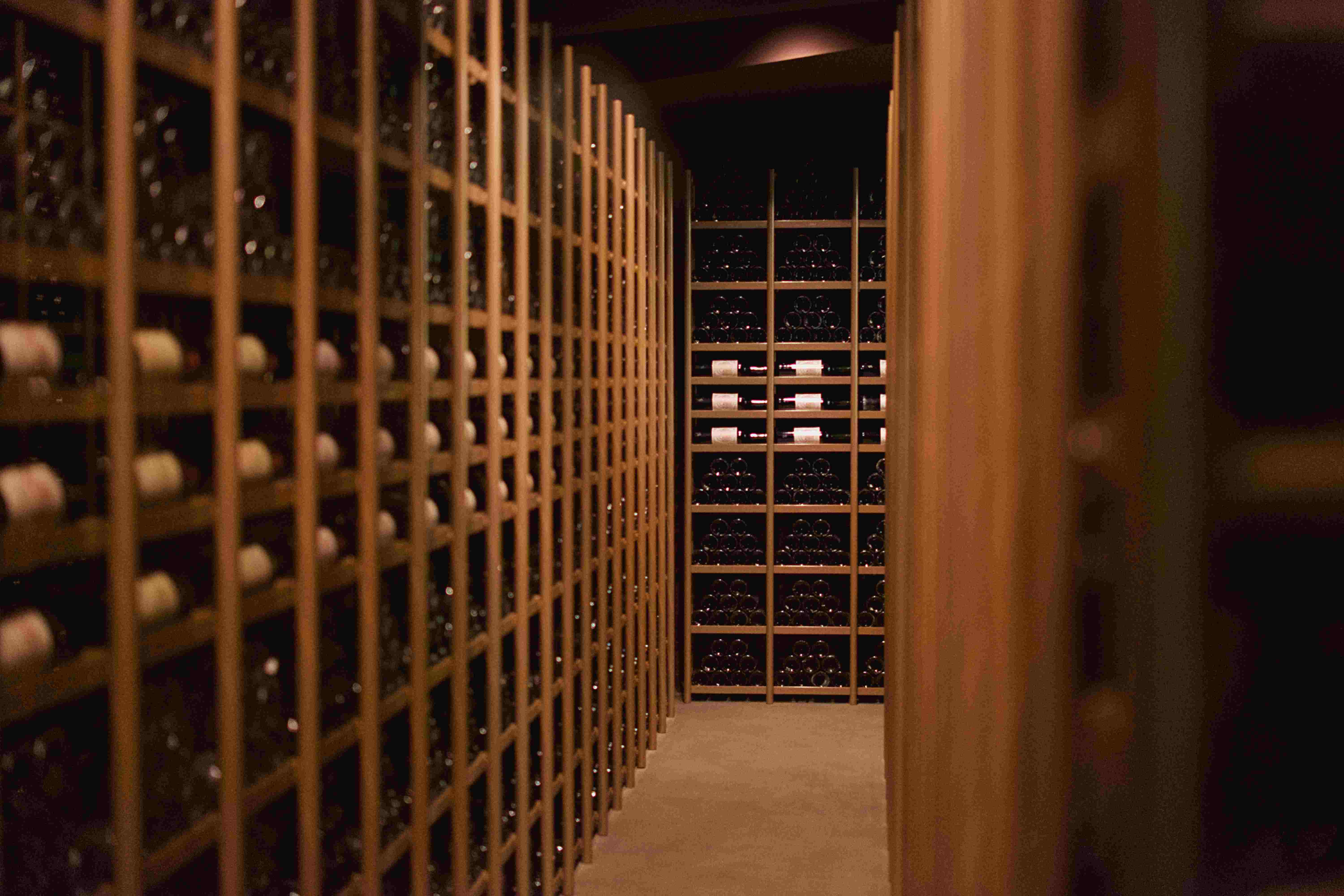 Wooden wine cellar racks filled with hundreds of dusty bottles
